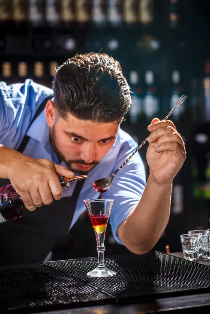 Barman préparant un cocktail à la cuillère chez Restoquali